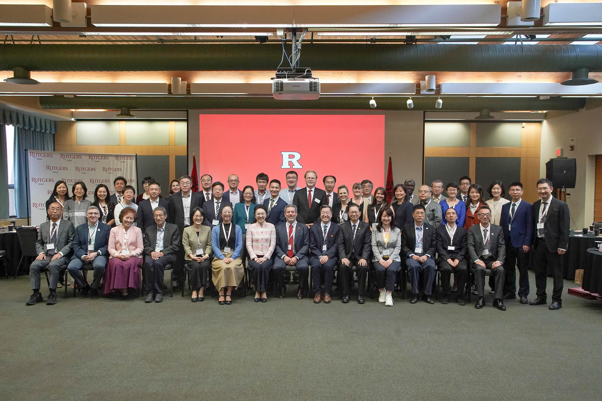 China Delegation visits Rutgers, group photo in front of red R banner