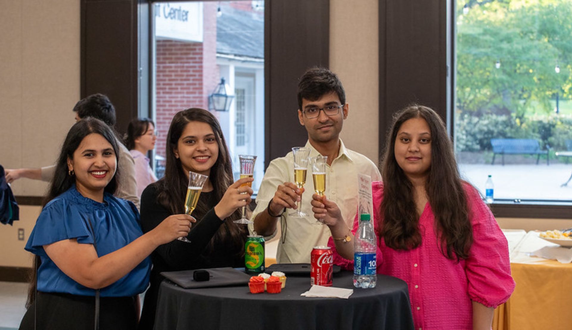 Four Rutgers students at Global Graduation Celebration, raising a toast
