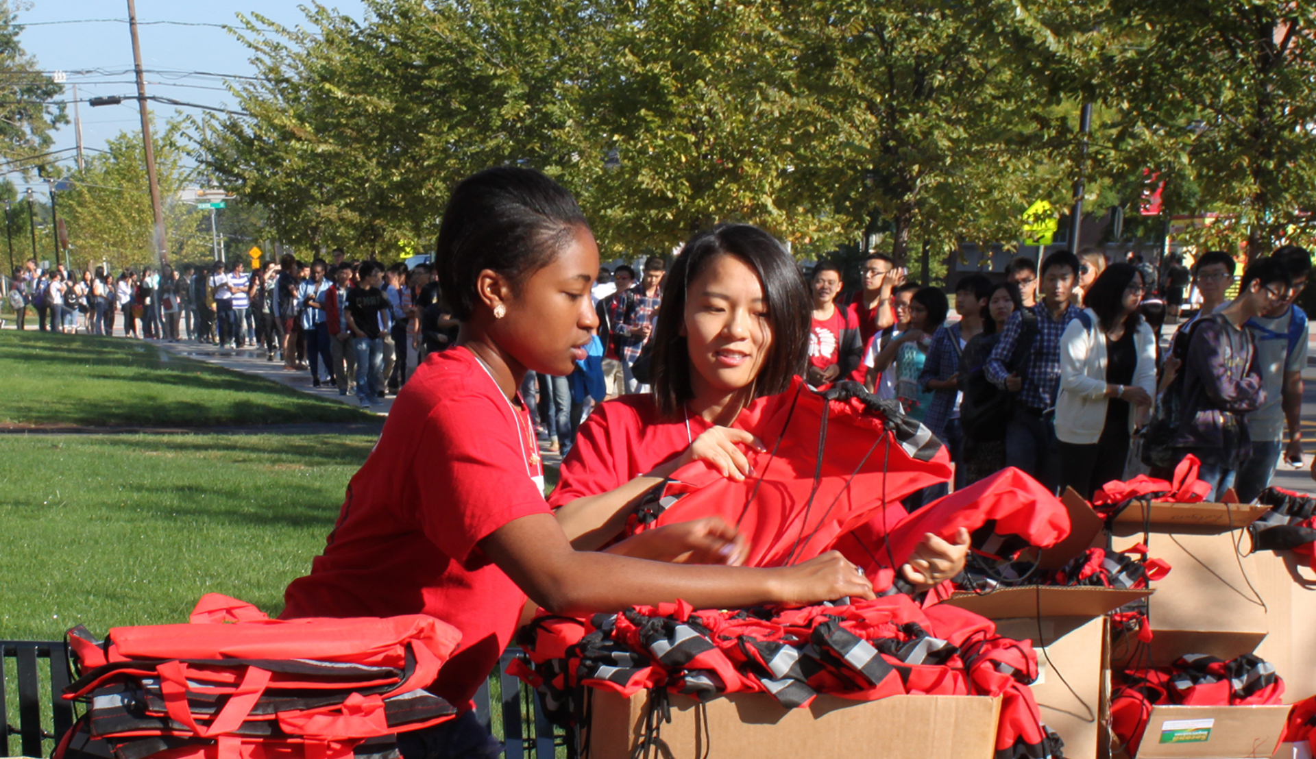 Rutgers Global – International Student Orientation, a long line of international students arrives on campus for orientation and receives a special Rutgers tote bag upon entry