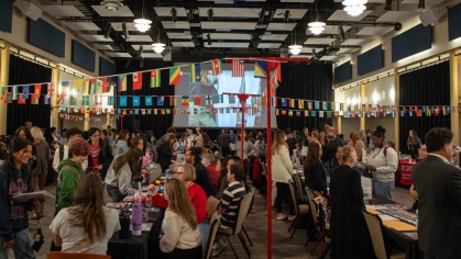 This lively image showcases the Rutgers Study Abroad Fair. The event space is adorned with colorful international flags, highlighting the global theme. Attendees, including students and faculty, engage with booths and displays, creating a vibrant and interactive atmosphere. It reflects the diverse opportunities available for studying abroad and fosters a sense of global community.