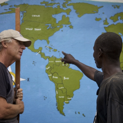 a man wearing a hat on the left and a man pointing at maps on the right