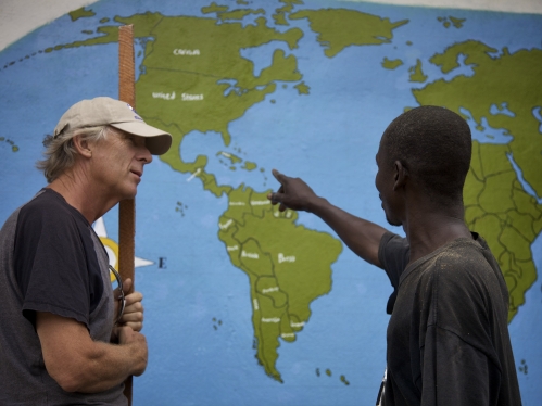 a man wearing a hat on the left and a man pointing at maps on the right