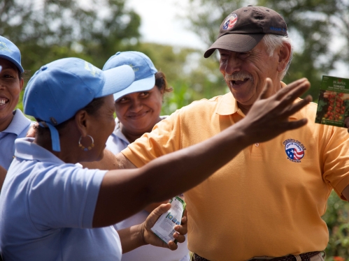 3 women in blue shirts and hats with a man in yellow shirt and brown hat