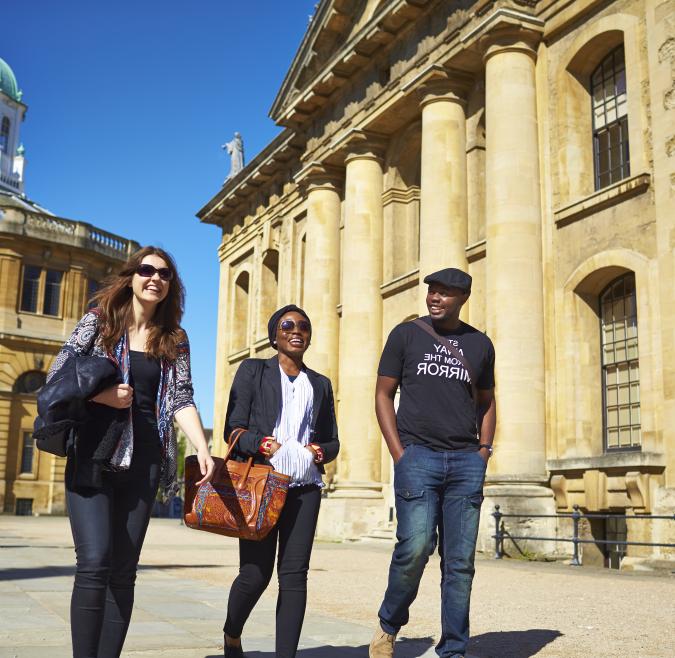 Three students walk through Oxford Brookes' campus on a sunny day