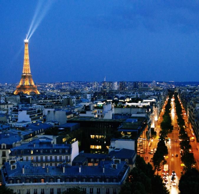 The Eiffel Tower is lit up and shining bright over the Paris skyline
