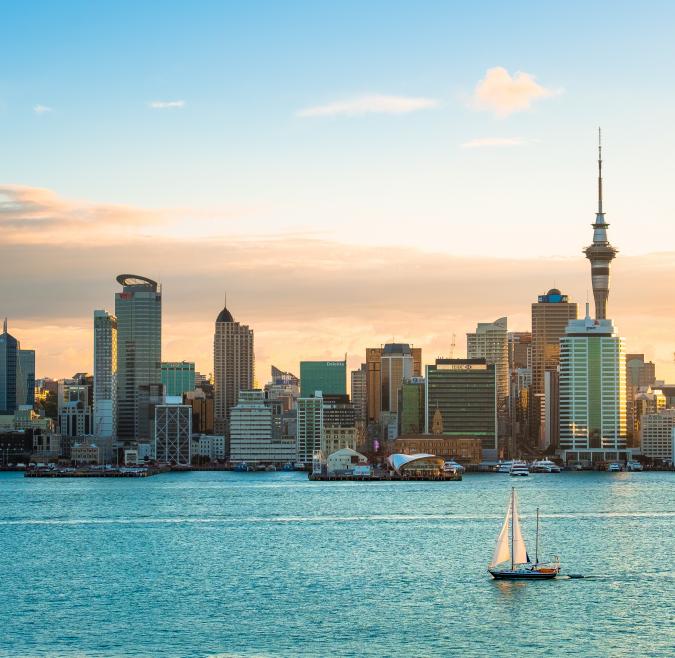 A sailboat in front of the Auckland skyline at dusk