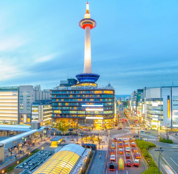 In the center of the image, a skyscraper towers over a business district of Kyoto at night