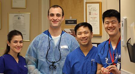 Rutgers Health - team of dental students and dentists pose holding dentures