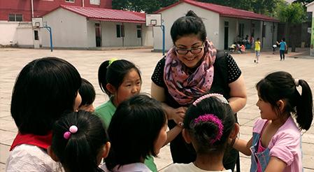 Rutgers Global - Service-Learning Abroad, female Rutgers student talks to a group of children in a schoolyard in China