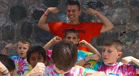 Rutgers Global - Rutgers Staff Employ Peace Corps Tradition, a Peace Corps volunteer (left) plays with a group of local children wearing tye-dye tee shirts at a youth center in Albania