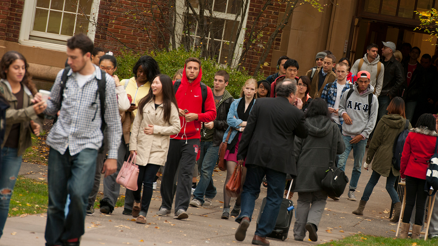 Rutgers Office of Diversity and Inclusion, a large group of students enter and exit a classroom buidling outdoors on the quad